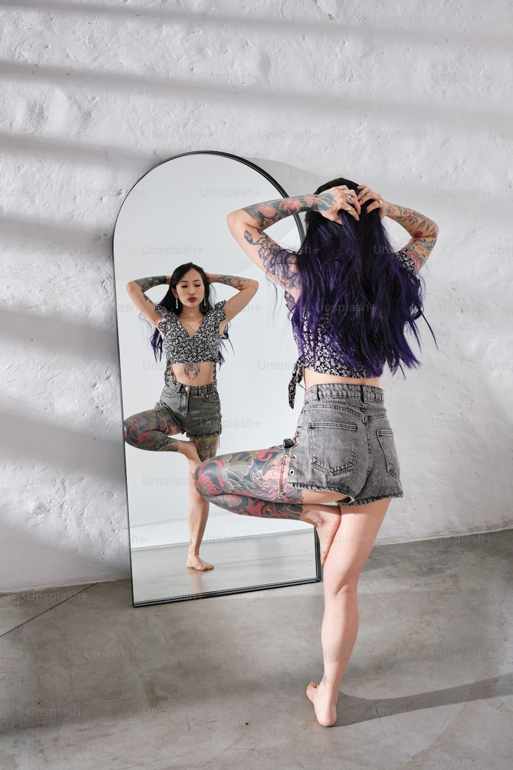 a woman with purple hair standing in front of a mirror