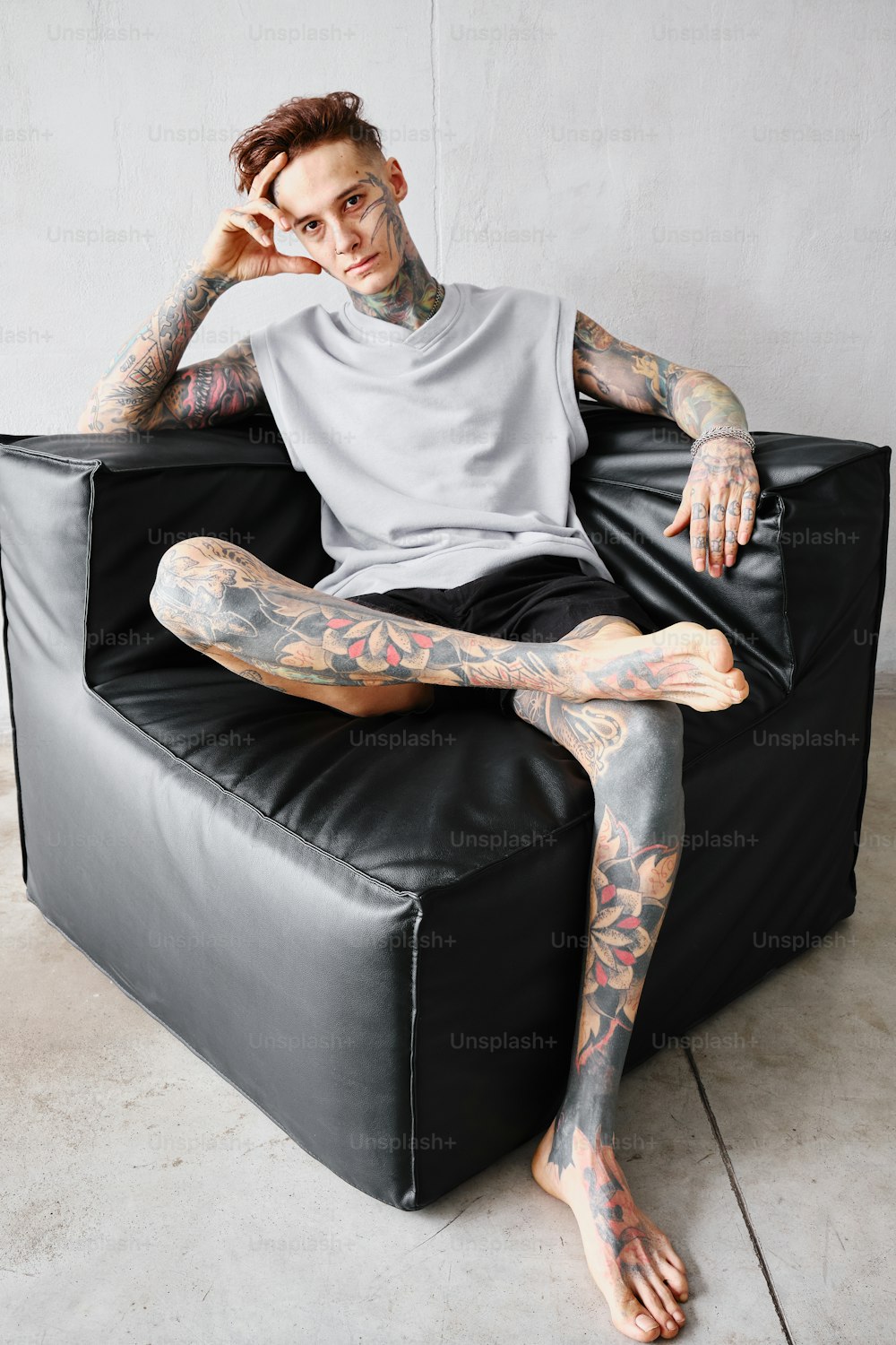 a tattooed man sitting on top of a black chair