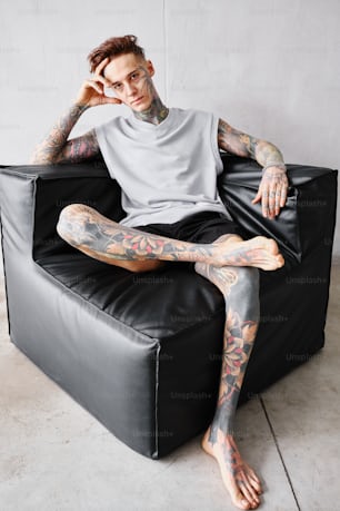 un homme tatoué assis sur une chaise noire