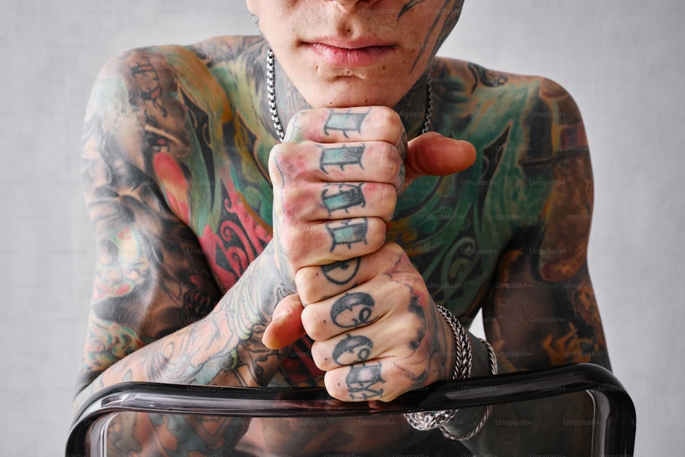 a tattooed man holding a suitcase with both hands