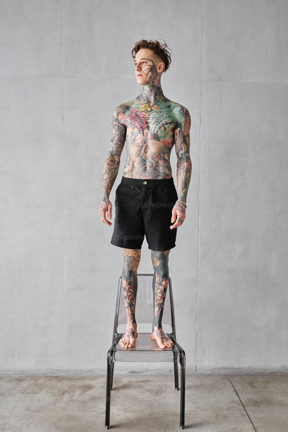 a man with tattoos standing on a chair