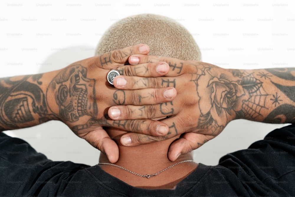 um homem com tatuagens cobrindo o rosto com as mãos