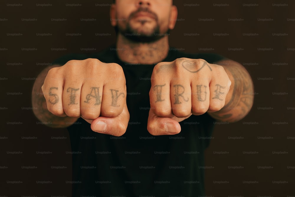 a man with a tattooed arm pointing at the camera