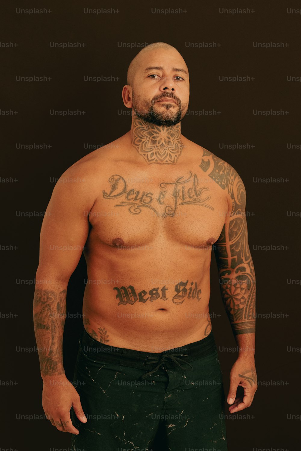 a man with a tattooed chest standing in front of a black background