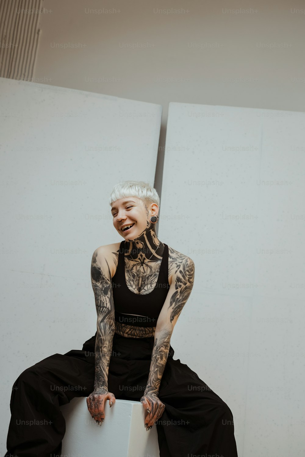 a tattooed woman sitting on top of a white box