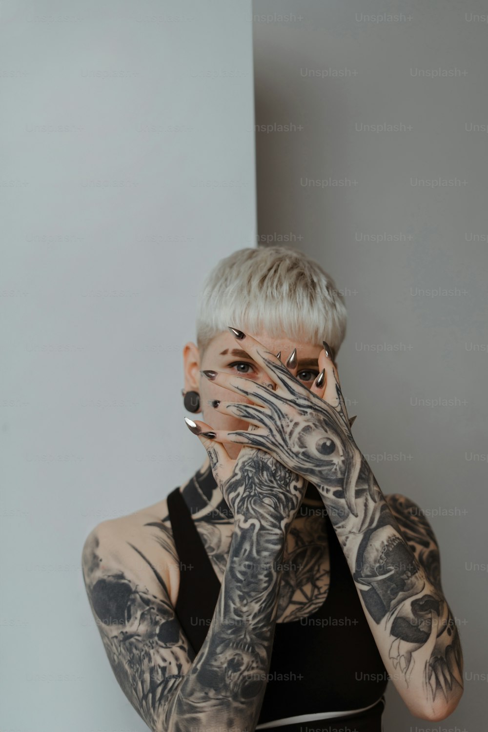 a tattooed woman covering her face with her hands