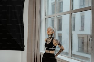 a woman with tattoos standing in front of a window