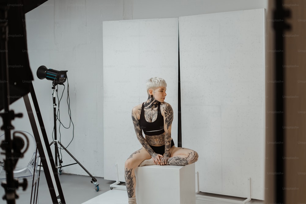 a woman with tattoos sitting on a cube