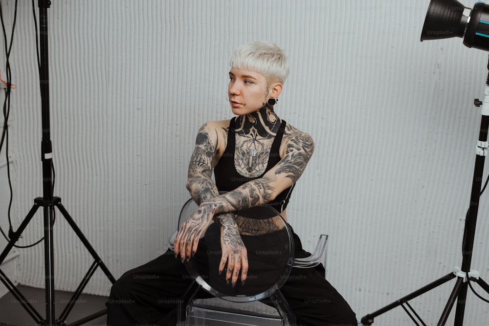 a tattooed woman sitting on a chair in front of a camera