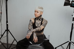 Una mujer tatuada sentada en una silla frente a una cámara