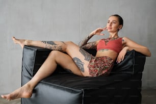 a woman with tattoos sitting on a black couch