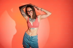a woman with tattoos and glasses posing for a picture