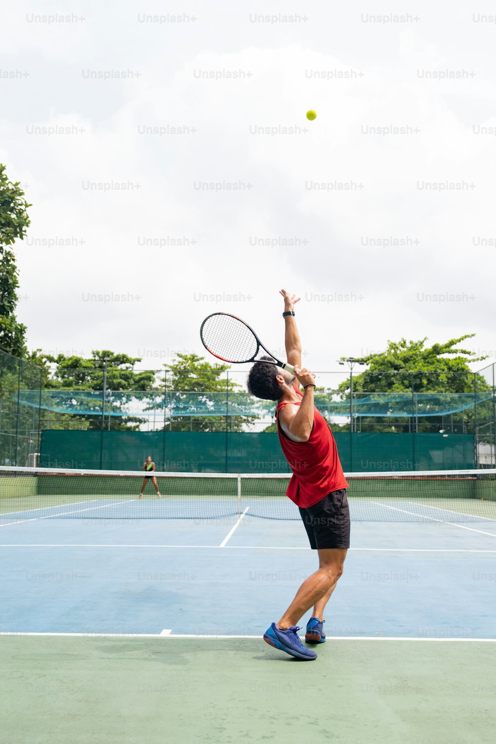a man in red shirt and black shorts playing a game of tennis