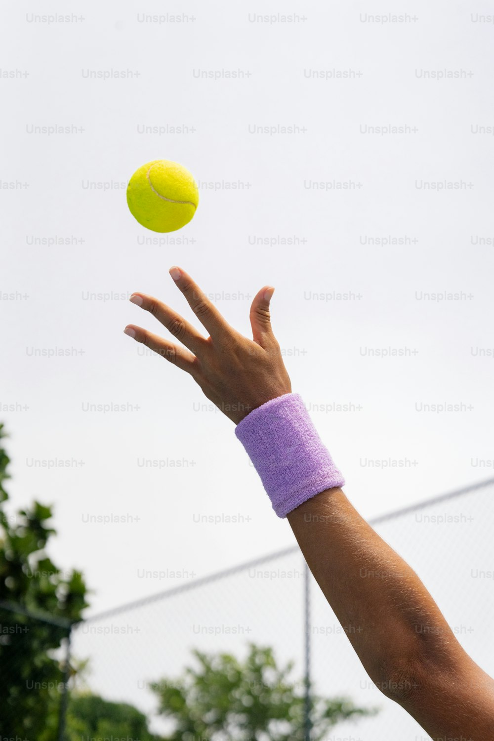 a person reaching up to catch a tennis ball