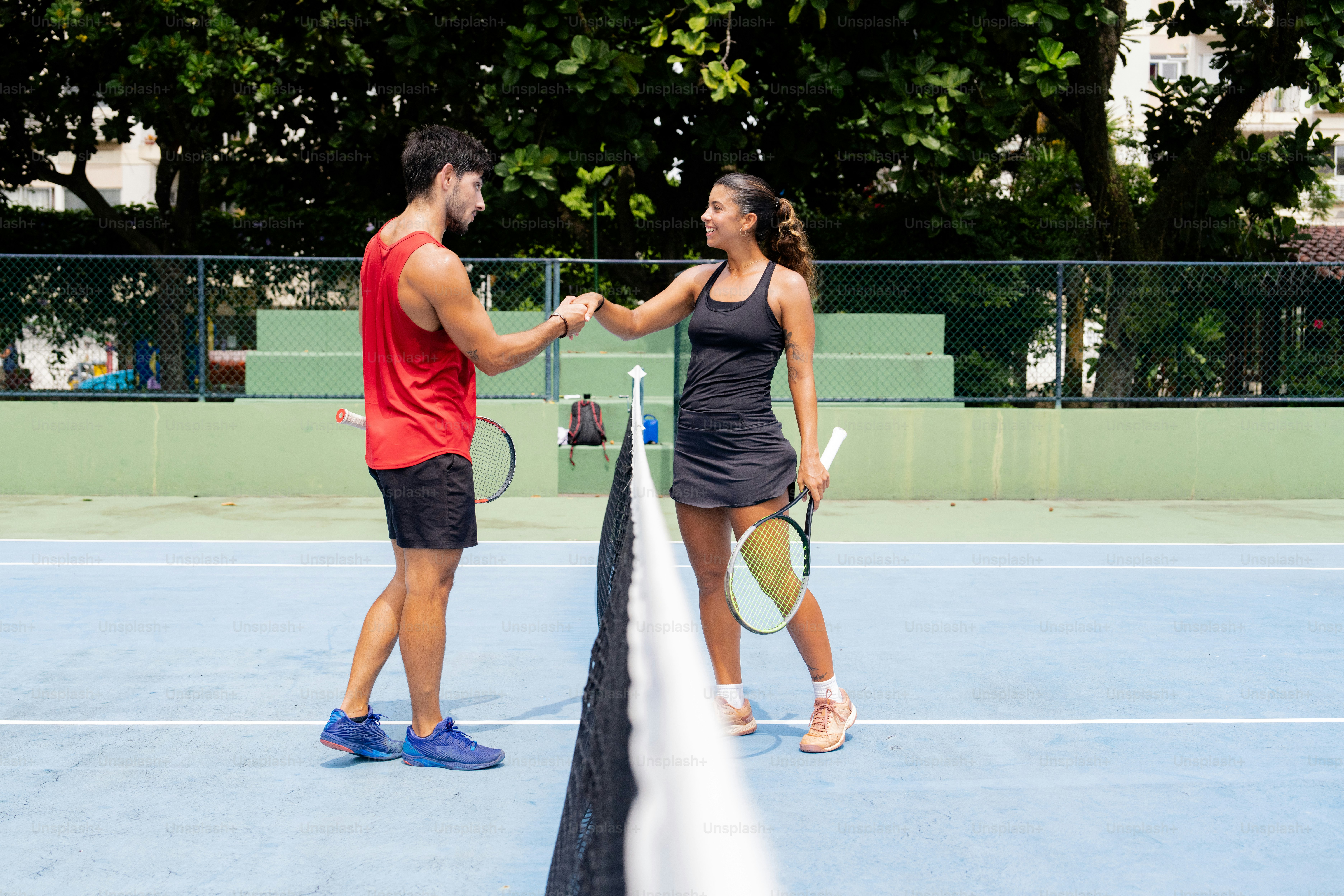 a man and woman shaking hands on a tennis court