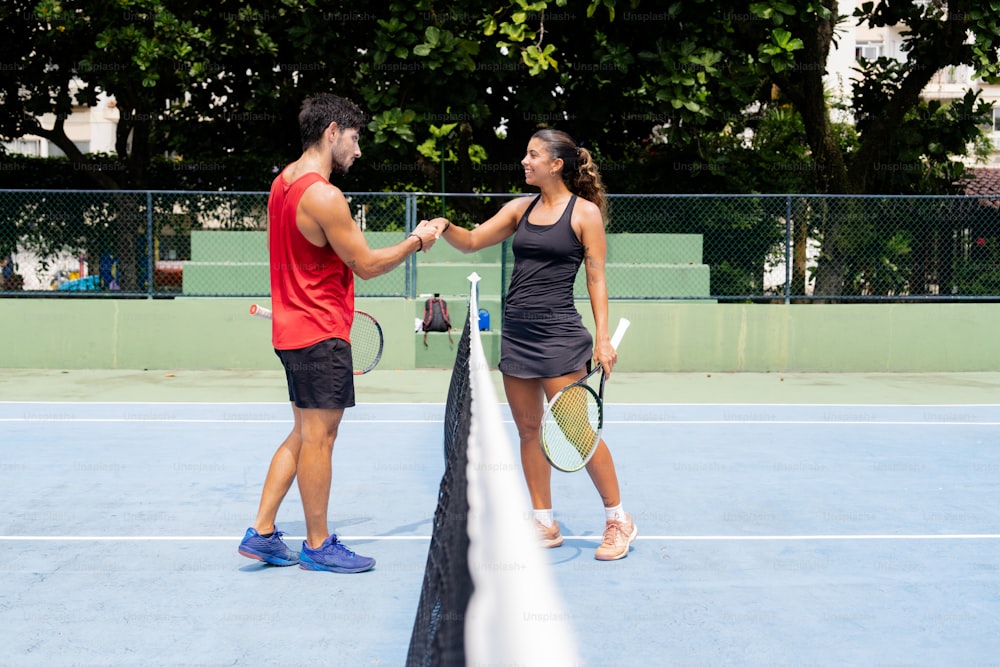 a man and woman shaking hands on a tennis court