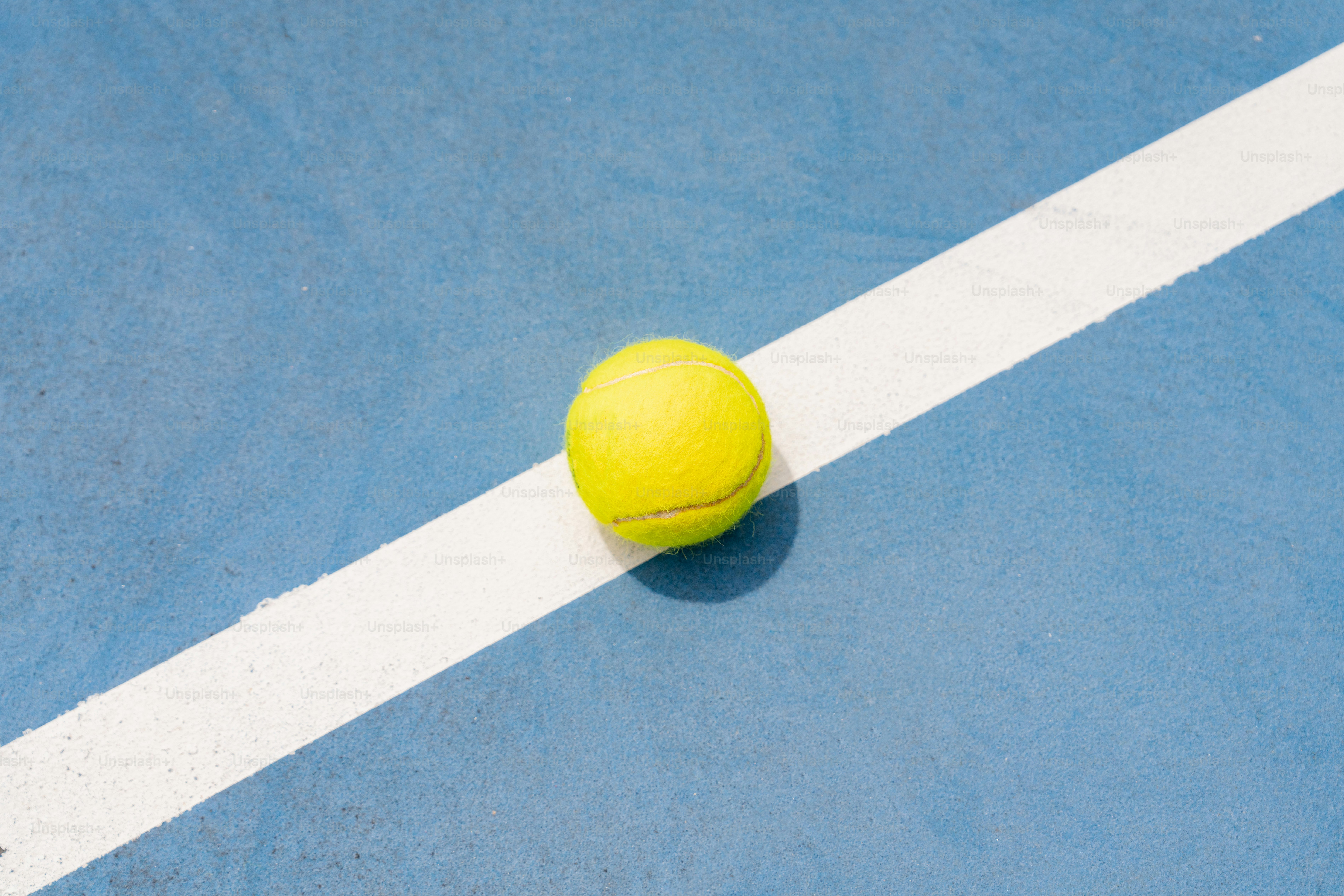 ein gelber Tennisball auf einem blauen Tennisplatz