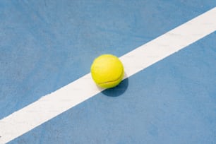 uma bola de tênis amarela em uma quadra de tênis azul