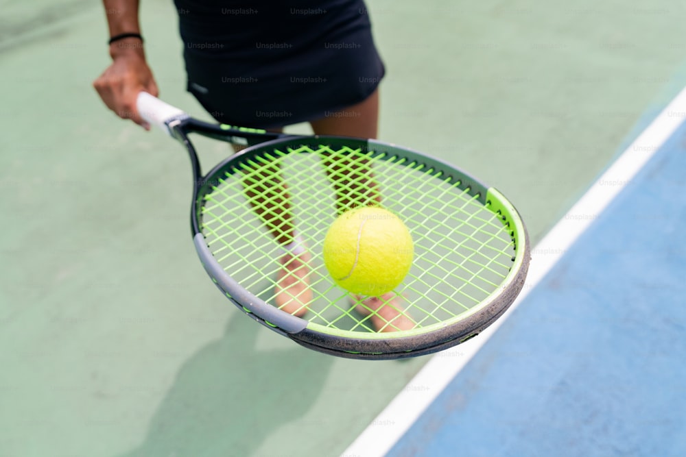 uma pessoa segurando uma raquete de tênis e uma bola de tênis
