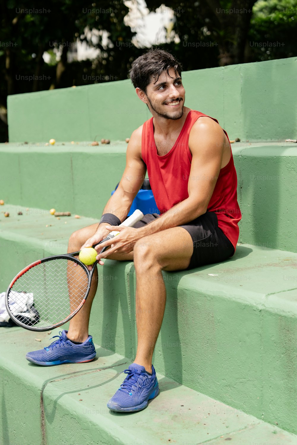 a man sitting on steps with a tennis racket and ball