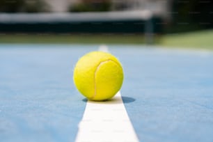 uma bola de tênis sentada na borda de uma quadra de tênis