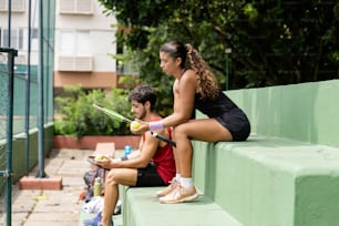 a woman holding a tennis racquet sitting next to a man