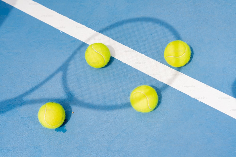 three tennis balls and a racket on a blue court