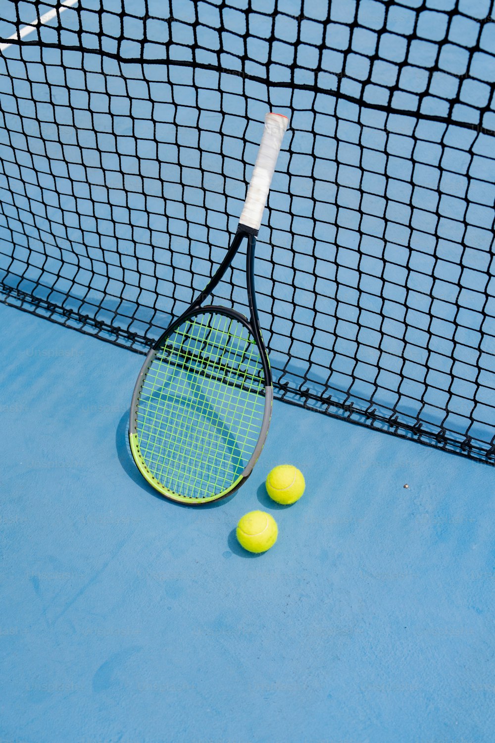 a tennis racket and three tennis balls on a tennis court