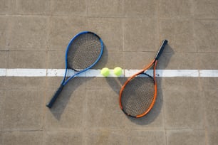 two tennis racquets and a tennis ball on the ground