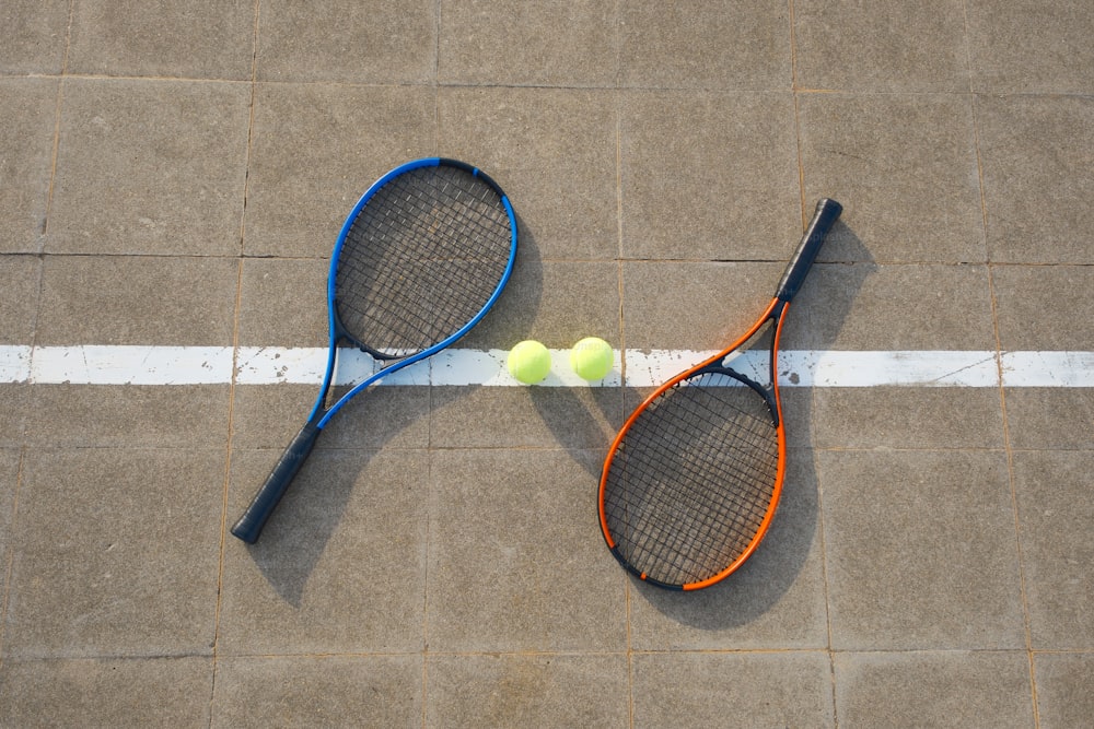 two tennis racquets and a tennis ball on the ground