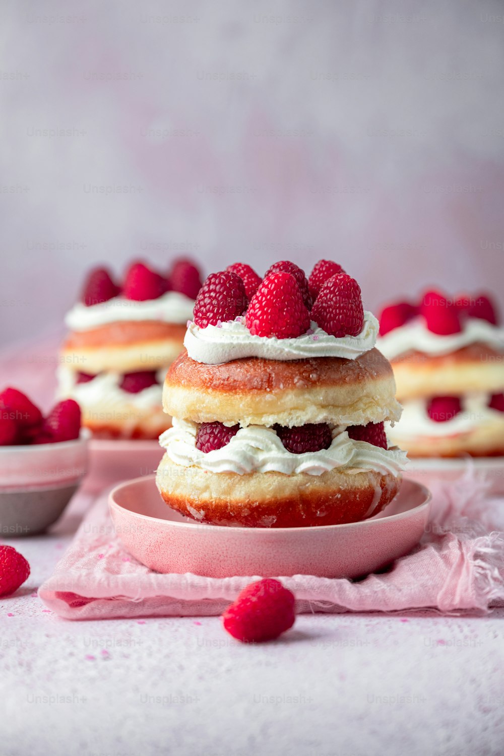 a stack of raspberry shortcakes on a pink plate