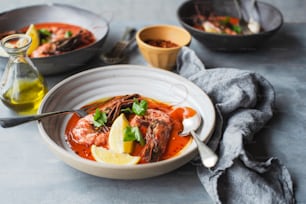 a bowl of soup with shrimp, lemon and parsley