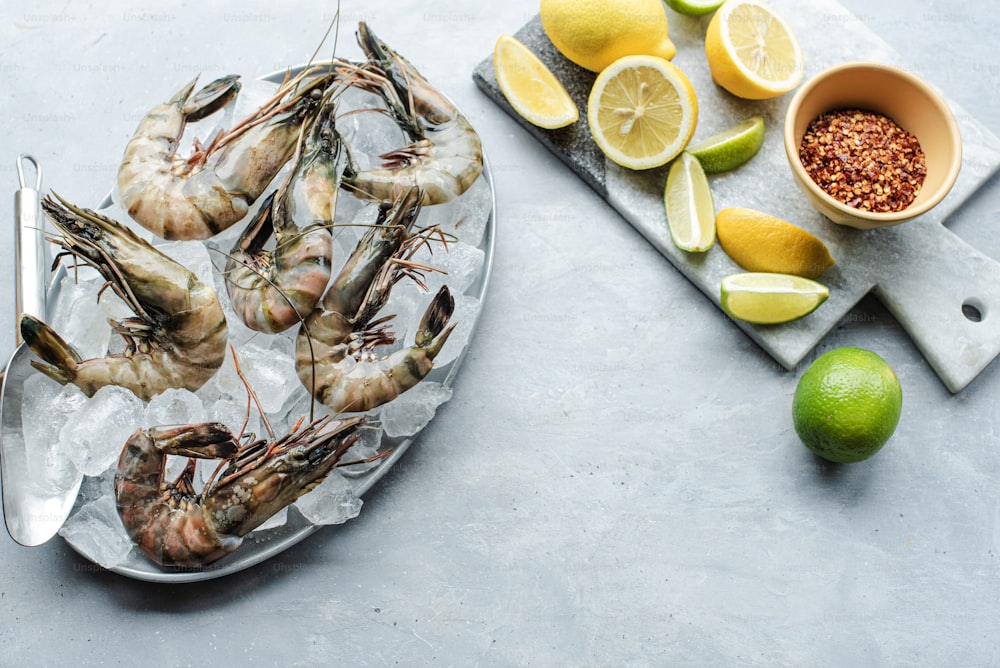 a plate of cooked shrimp next to a bowl of lemons and limes