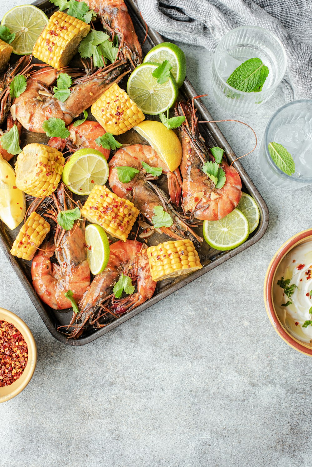 a tray of shrimp, corn, and limes on a table