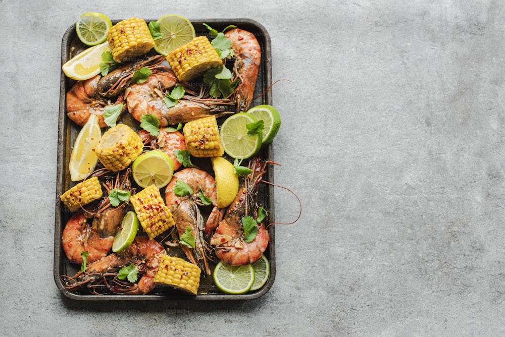 a tray filled with shrimp, corn, and limes