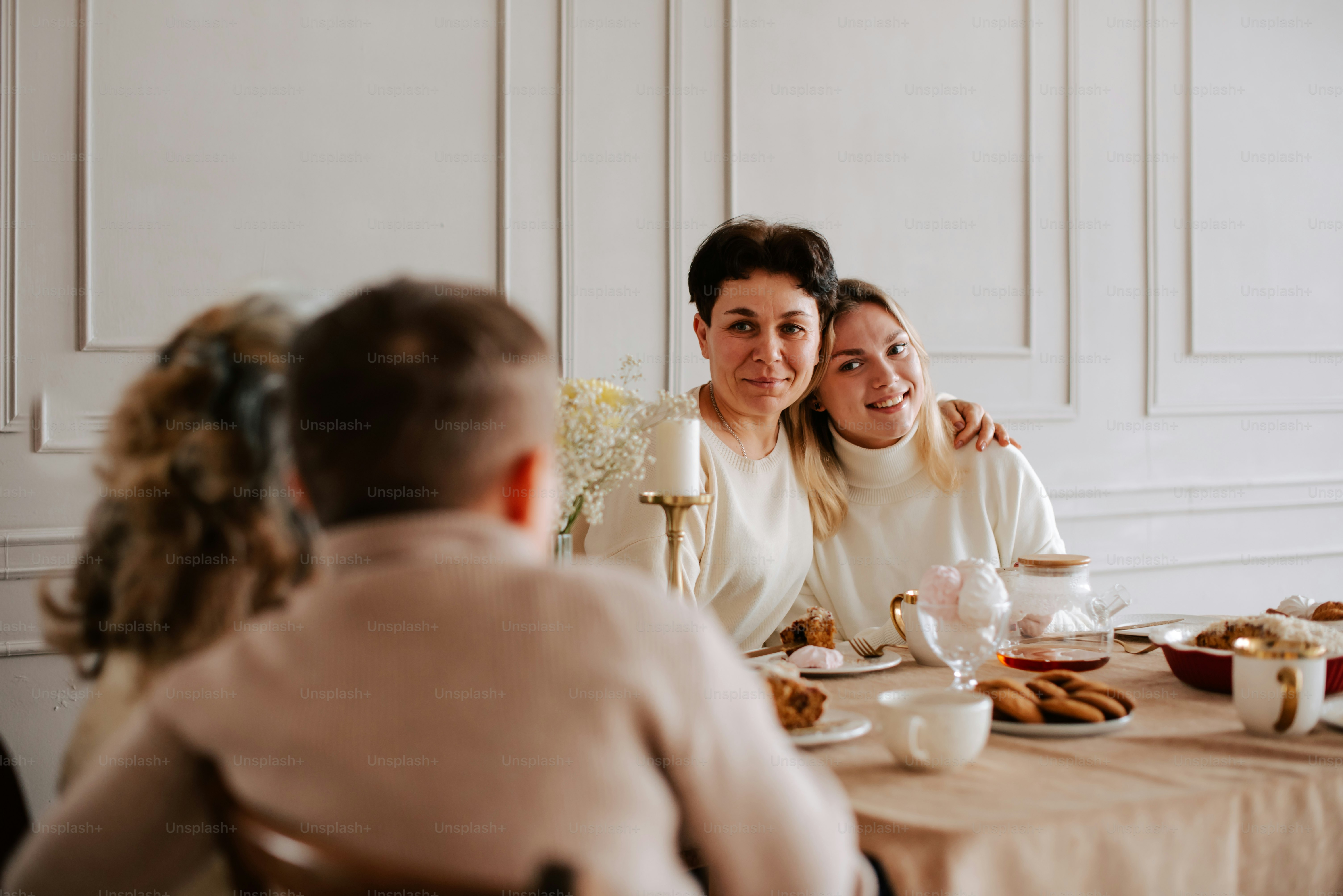 a couple of women sitting at a table with food