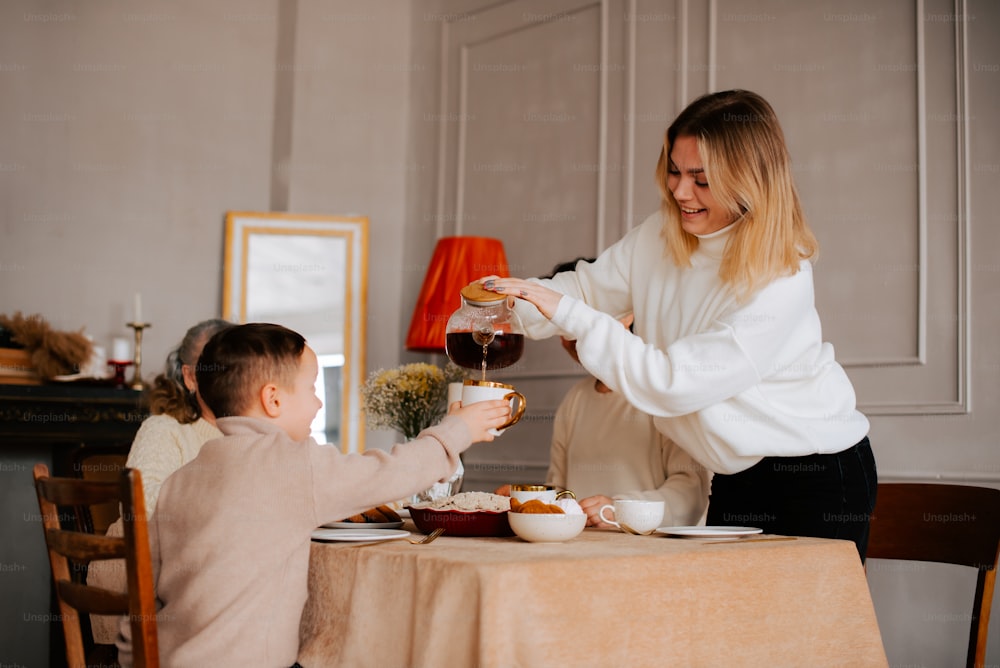 a woman pouring a glass of wine to a child at a table