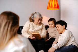 una donna seduta su un divano che legge un libro a due bambini