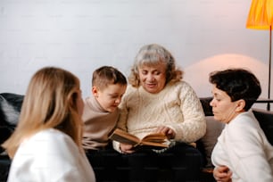 a woman sitting on a couch reading a book to two children