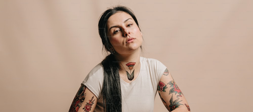 a woman with long black hair and tattoos on her arms