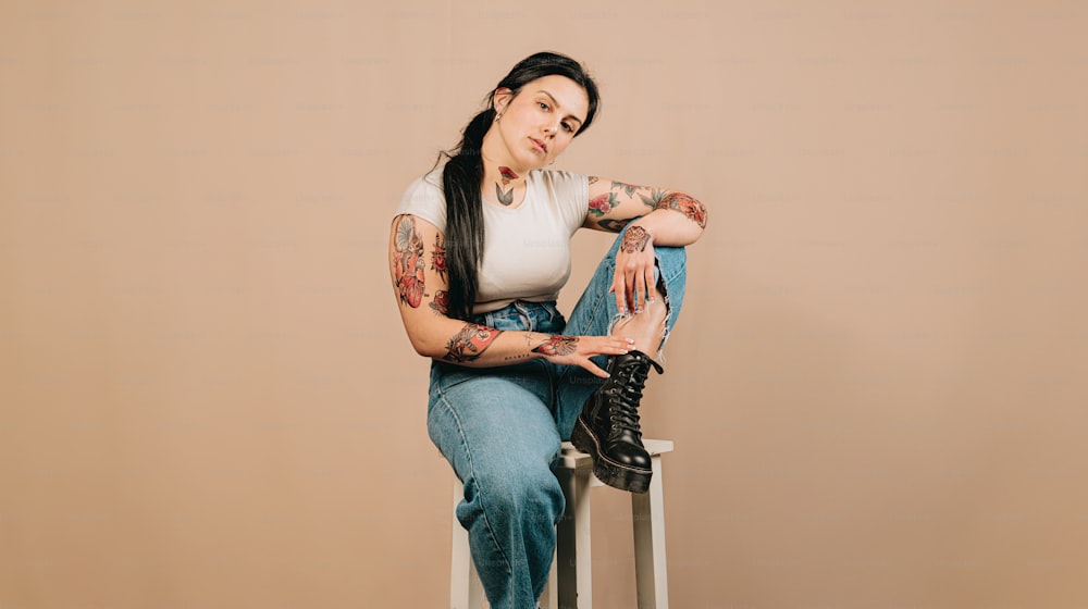 a woman with tattoos sitting on a stool