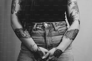uma mulher com tatuagens segurando as mãos nos bolsos