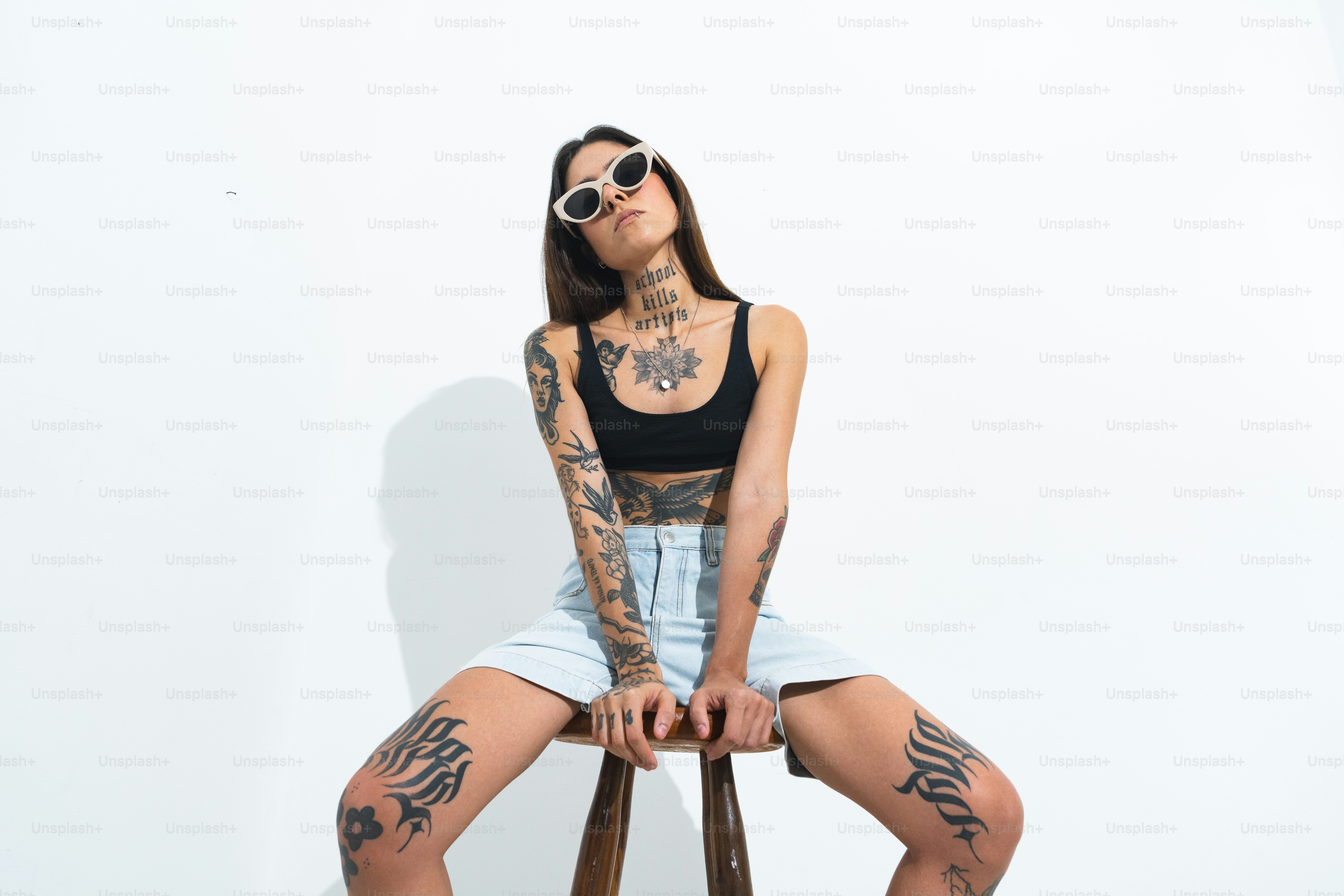 eine Frau mit Tätowierungen sitzt auf einem Stuhl