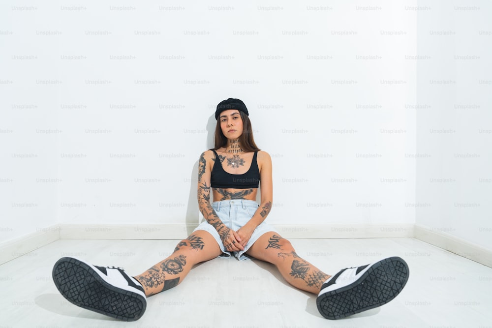 una donna con tatuaggi seduta sul pavimento