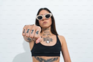 Une femme avec un bras tatoué pointant vers la caméra