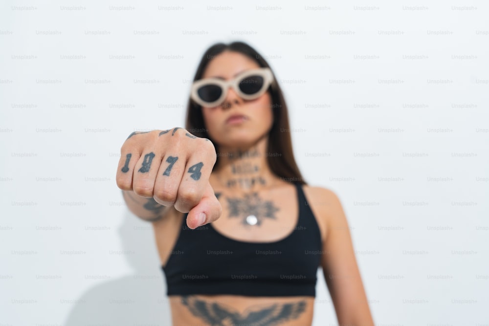 uma mulher com um braço tatuado apontando para a câmera