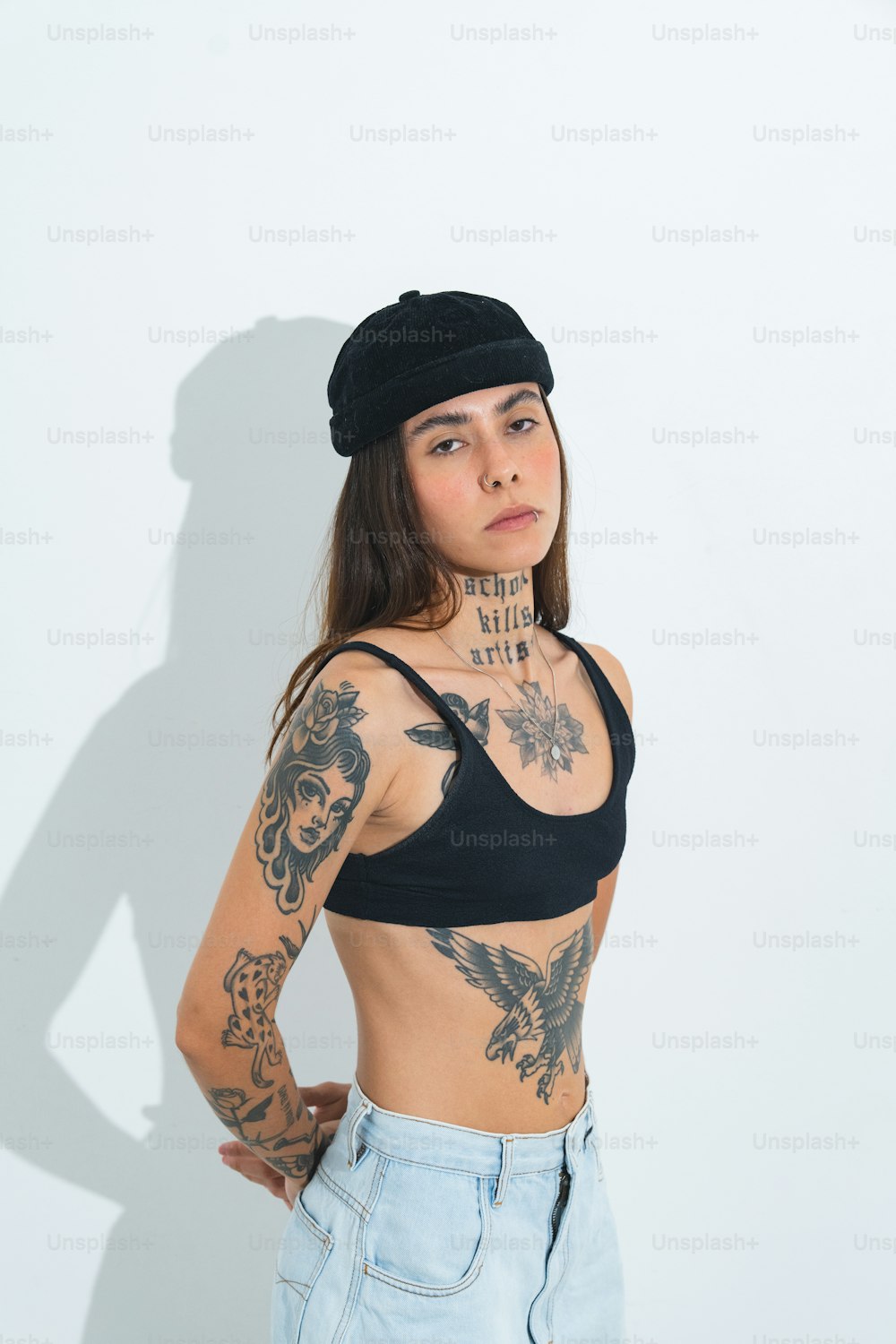una mujer con tatuajes de pie frente a una pared blanca