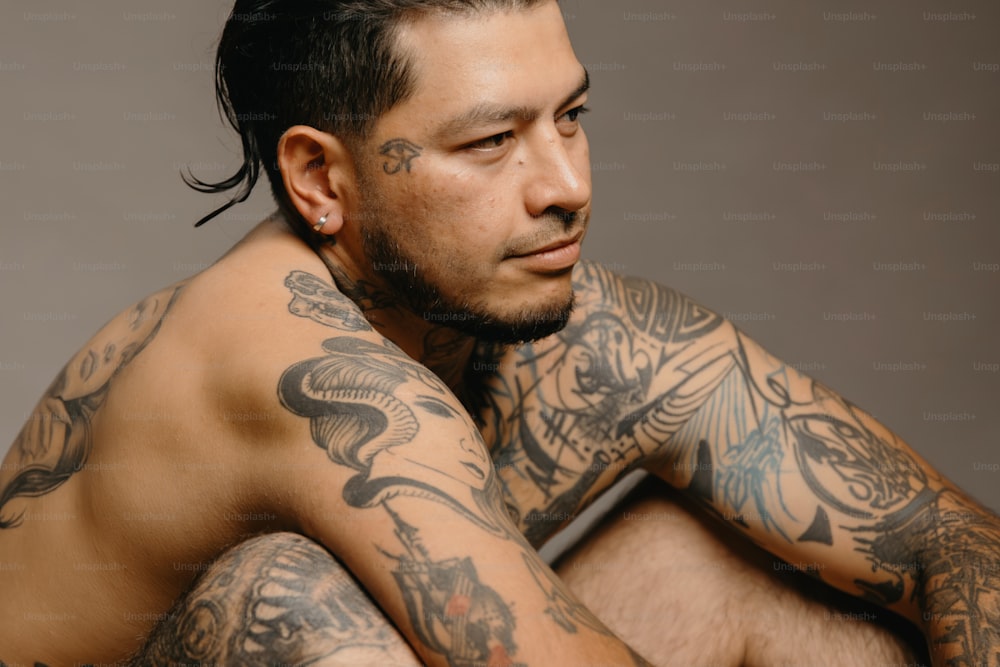 un homme avec des tatouages sur les bras et la poitrine