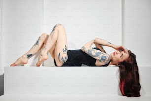 a woman with tattoos laying on a ledge