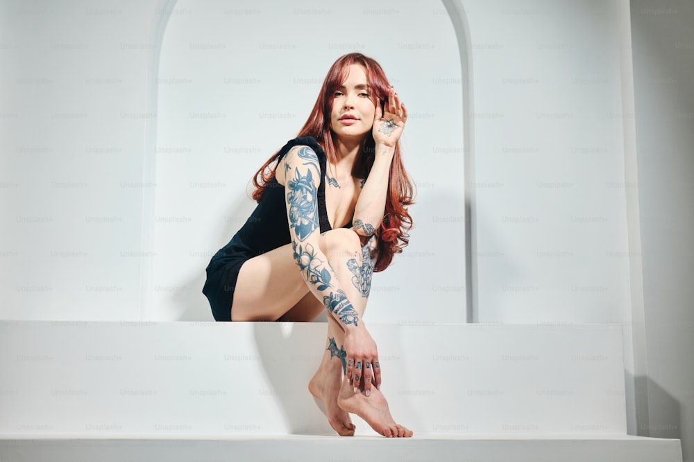 une femme avec des tatouages assise sur un rebord